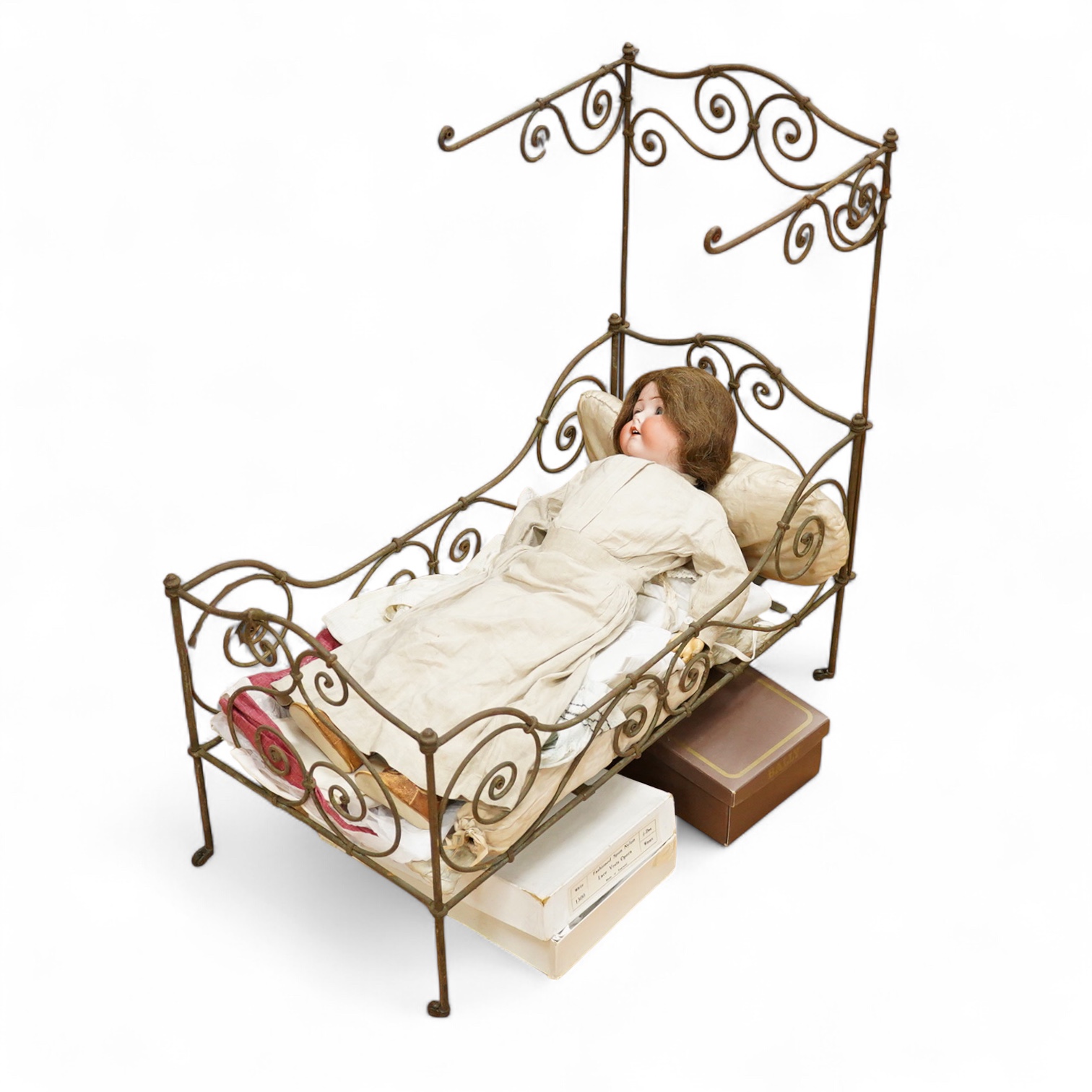 An Heubach Koppelsdorf bisque doll, mould 320 with sleeping eyes, open mouth and jointed composition body, together with a tubular and wrought metal half-tester bed, on casters, related clothing and bedding, doll 64cm